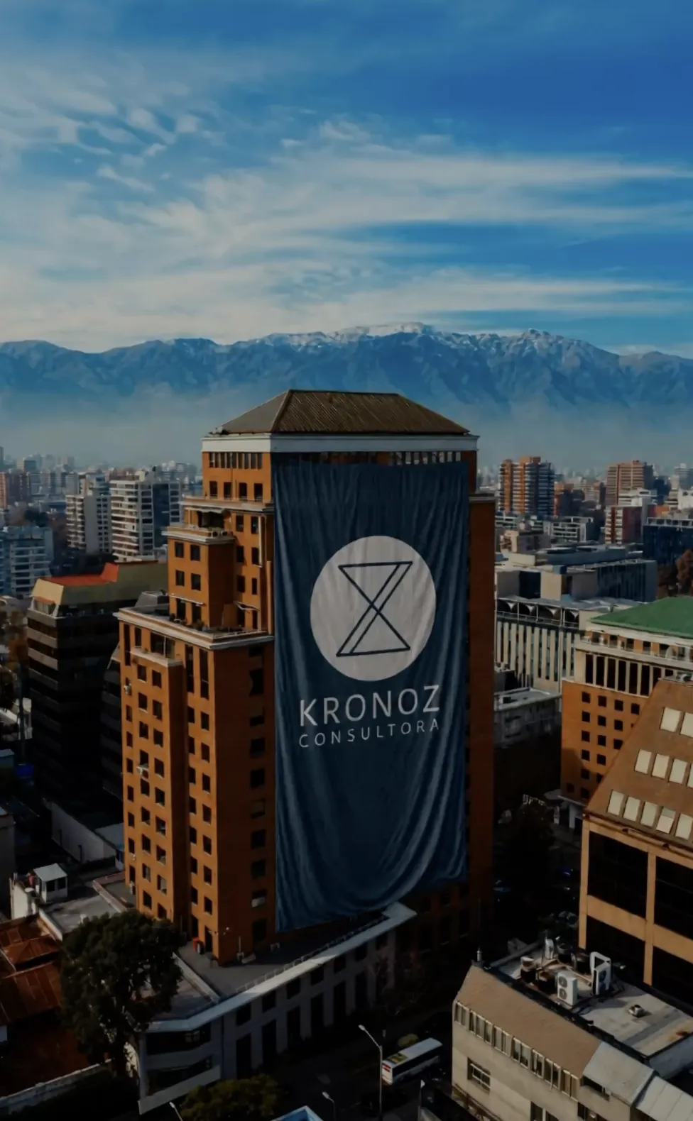 Edificio en Santiago con un gran lienzo de Consultora Kronoz y la cordillera de los Andes al fondo