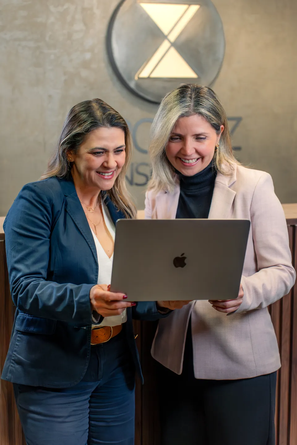 Dos integrantes del equipo Kronoz revisan información en un notebook frente al logo de la consultora